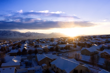 The sun rises over a snow-covered suburban neighborhood
