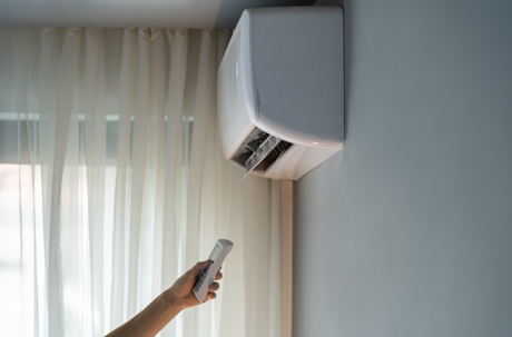 A person uses a remote control to operate the AC