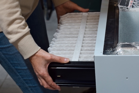 A person inserts a clean air filter into an HVAC system.