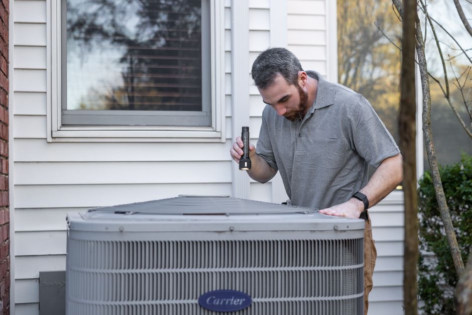 homeowner inspecting old air conditioning unit in Utah backyard summer